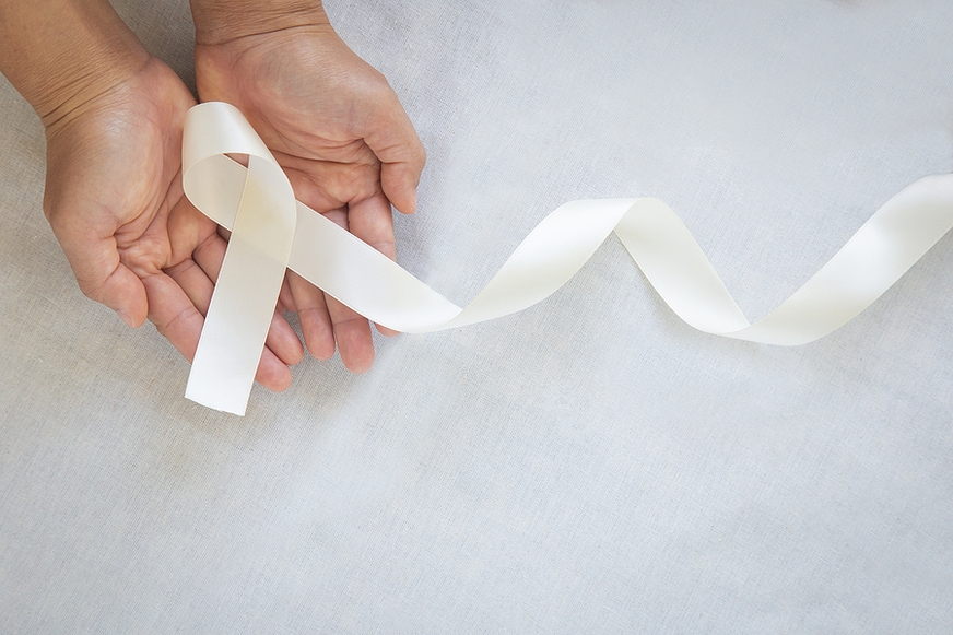 white ribbon forms bow in outstretched hands