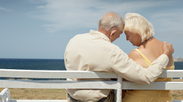 Elderly couple on a bench looking out to sea